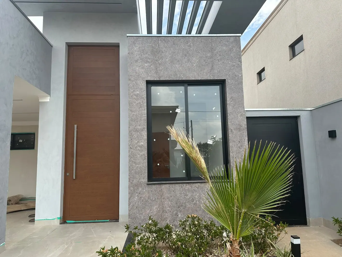 Porta de entrada alta amadeirada em residência contemporânea